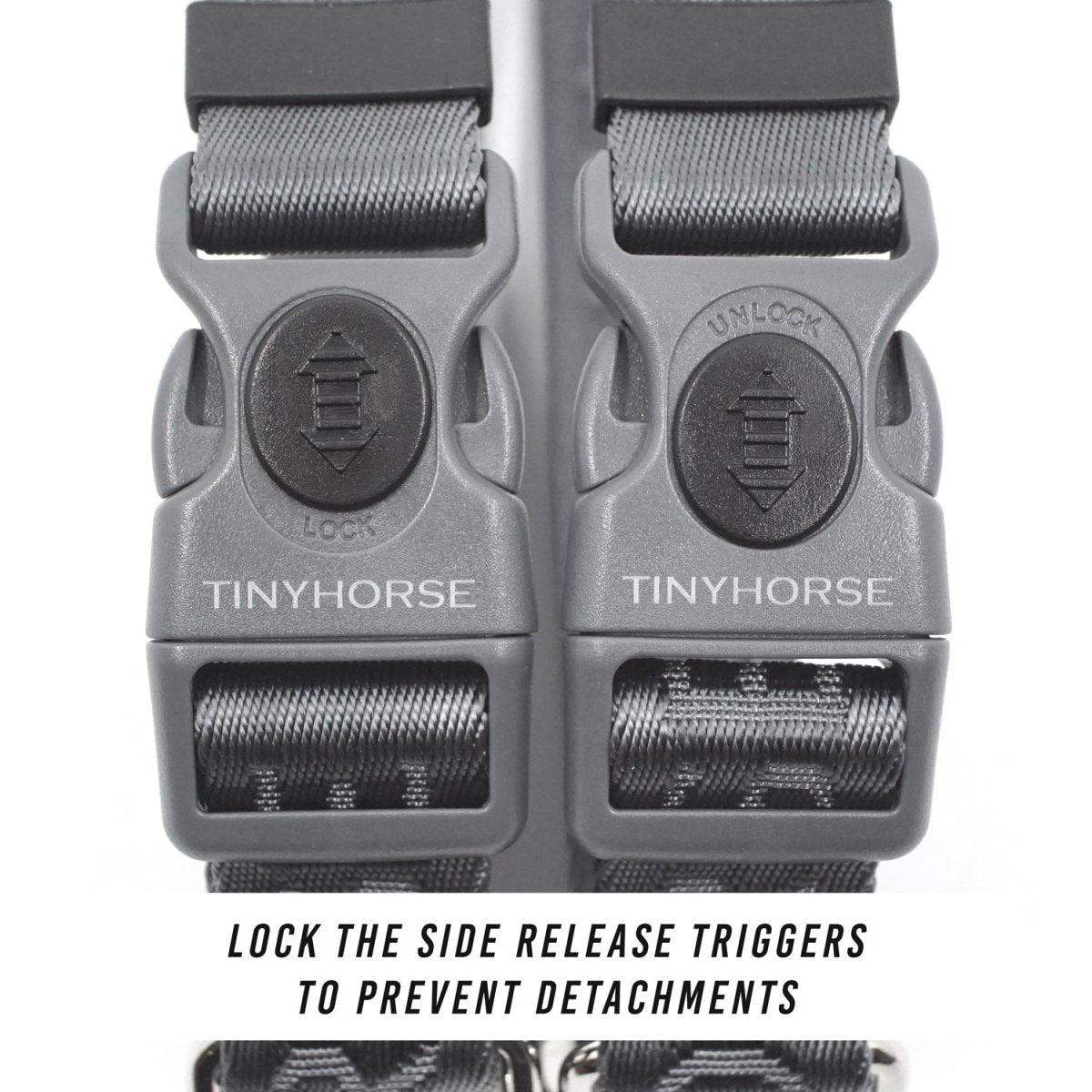 Close up of a collar buckle that has a button for locking and unlocking the side release. The buckles are grey and the buttons are black. The background is white.