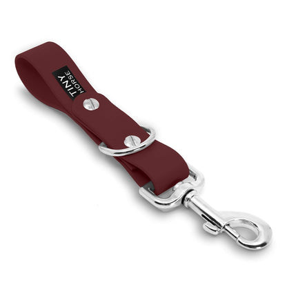 A burgundy Sidekick Hands free dog walking attachment with silver trigger clip on a white background.