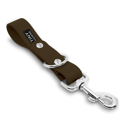 A dark brown Sidekick Hands free dog walking attachment with silver trigger clip on a white background.