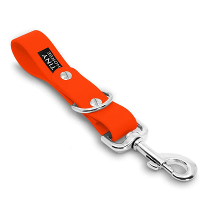 A neon orange Sidekick Hands free dog walking attachment with silver trigger clip on a white background.